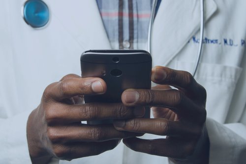 Doctor with coat holding a phone in hand
